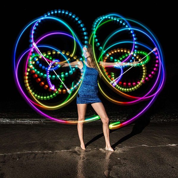 Lumina V2 Light Up Twirling Baton with a model on the beach at night with colorful lights