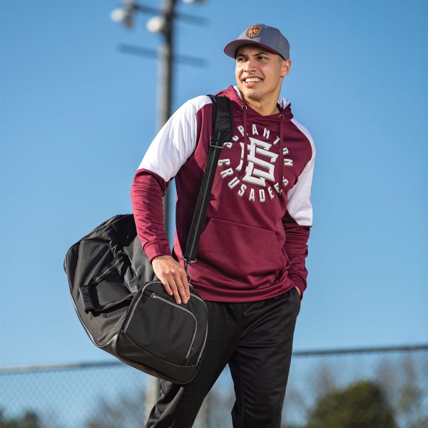 Man on a field with blue sky holding a Holloway Rivalry Backpack Duffel Bag